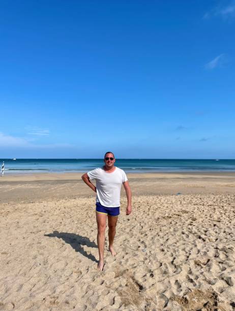 istock Man on a beach in swimming shorts. 1661353569