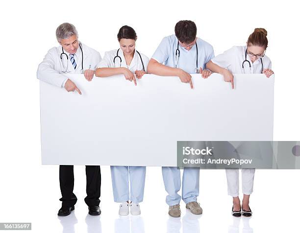 Foto de Equipe Médica Segurando Um Banner Em Branco e mais fotos de stock de Apontar - Sinal Manual - Apontar - Sinal Manual, Doutor, Mover para baixo