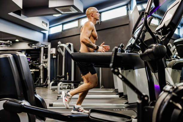 istock Muscular man jogging on treadmill in the gym 1661369330