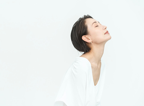 Profile of a beautiful Japanese woman.white background studio/wearing white clothes/upper body.