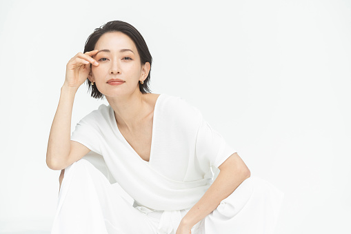 Profile of a beautiful Japanese woman./white background studio/wearing white clothes. /Whole body.