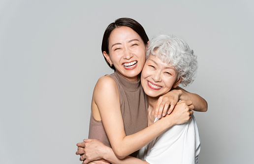 Two healthy Japanese women are smiling and hugging each other.