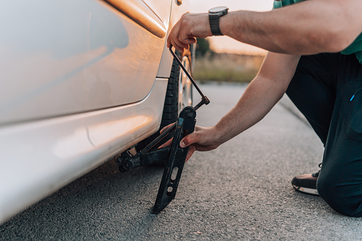 Confronted with a flat tire, the young man tackles the challenge of changing it, determined to continue his journey