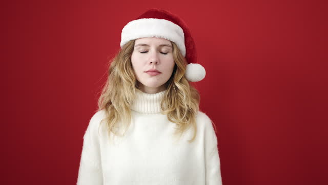 Young blonde woman smiling confident wearing christmas hat over isolated red background