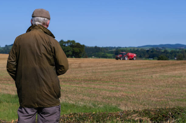 istock Senior man watching a tractor in a field 1661410993