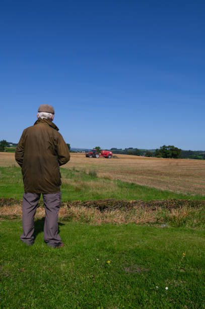 istock Retired farmer watching a tractor in a field 1661412092
