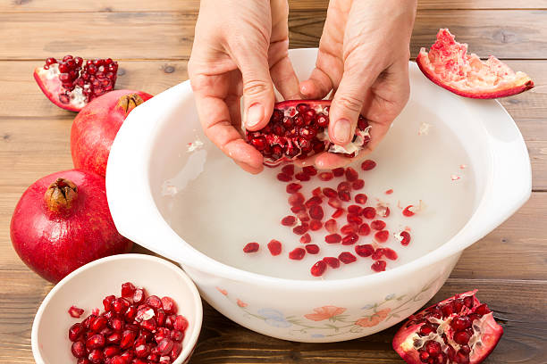 Seeding a pomegranate Hands seeding a pomegranate with the water method superfruit stock pictures, royalty-free photos & images