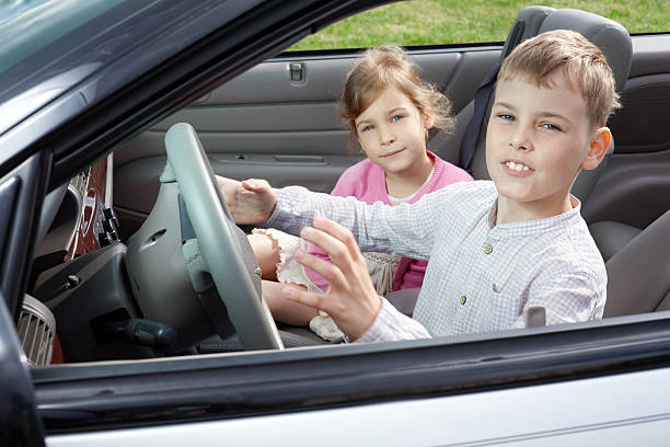 istock Boy and his sister sits on driver seat in car 166142047