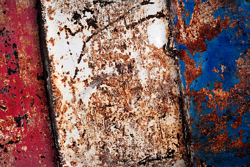 Detail of corroded rusty barrel metal texture that is red white and blue