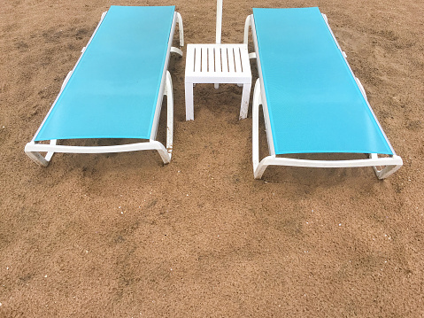 Empty lounge chairs and plastic coffee table at the beach