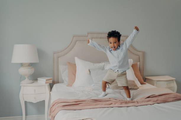 istock Adorable cute kid jumping cheerfully on bed and having fun at home 1661436028