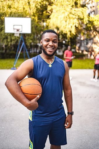 Portrait of a black male basketball player holding ball on court