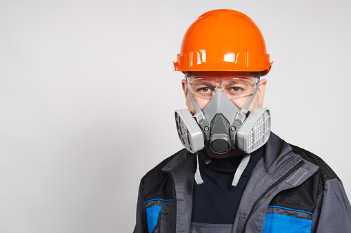 A man wearing a helmet, respirator and goggles on a white background.