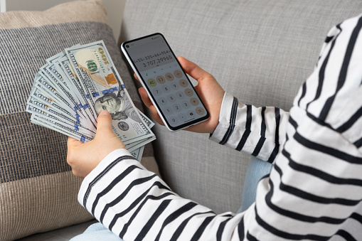 Hundred-dollar bills and a smartphone in the hands of a person