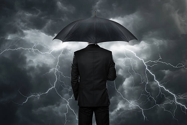 Trouble ahead Businessman with umbrella standing in front of stormy clouds emergency shelter photos stock pictures, royalty-free photos & images