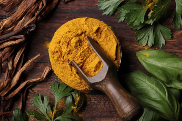 Turmeric powder with scoop Turmeric powder with scoop laid on seaweed and basil allspice stock pictures, royalty-free photos & images