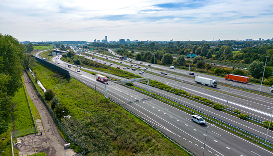 Aerial view of traffic and overpasses, city skyline on the horizon.