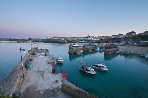 A tranquil scene of Newquay harbour after sunset. This fishing village is located on the north coast of Cornwall and is a popular tourist destination. 