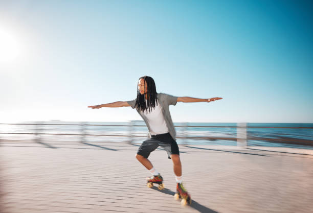 Man roller skating on the promenade at the beach during a summer holiday for fun and exercise. Young, fit and healthy guy skating for a fitness workout on boardwalk in nature by the ocean on vacation hombre patinando sobre ruedas en el paseo marítimo de la playa durante unas vacaciones de verano para divertirse y hacer ejercicio. chico joven, en forma y saludable patinando para un entrenamiento físico en el paseo marítimo en la naturaleza junto al o