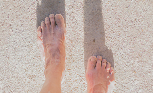 Bare feet, withered and worn skin, an older person walking.