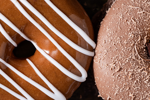 Macro photo of 2 delicious chocolate donuts. One with creamy white glazed and the other with powdered moka.