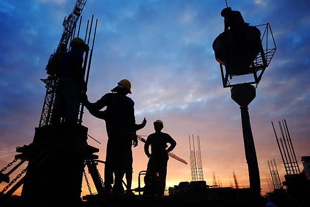 Silhouettes of workers at a construction site at dusk stock photo