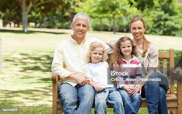 Two Parents Holding Their Children While Sitting On Park Bench Stock Photo - Download Image Now