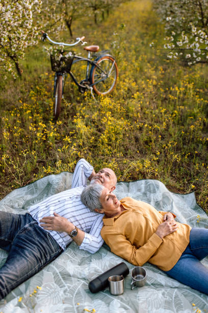 Senior couple resting on a picnic blanket in nature.