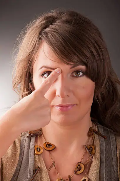 Woman doing EFT on the end of eyebrow point. Emotional Freedom Techniques, tapping, a form of counseling intervention that draws on various theories of alternative medicine.