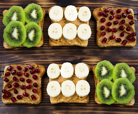 Sandwiches with fruit and peanut butter on the wooden background. Top view. Close-up.