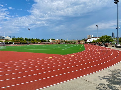 Eight-lane red outdoor track surrounding a green astro-turf football and soccer playing field at Denny Farrell Riverbank State Park on a summer day in West Harlem, New York City