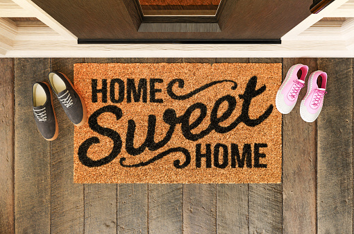 Home Sweet Home doormat with man and woman shoes on the porch at the front door.