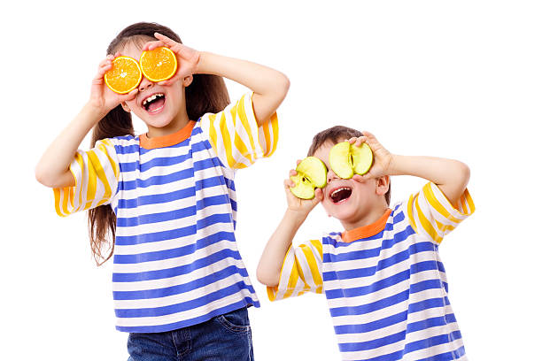 dois engraçado crianças com frutas de olhos - isolated on white fun orange food - fotografias e filmes do acervo