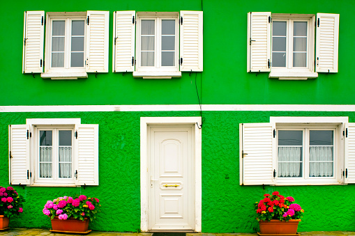 Green colored house facade seen from the street, closed front door, windows, traditional country house. Tapia de Casariego, Asturias, Spain.