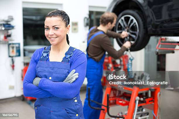 Mujer De Pie Mecánico En Un Garaje Foto de stock y más banco de imágenes de Garaje de reparación - Garaje de reparación, Mujeres, Adulto