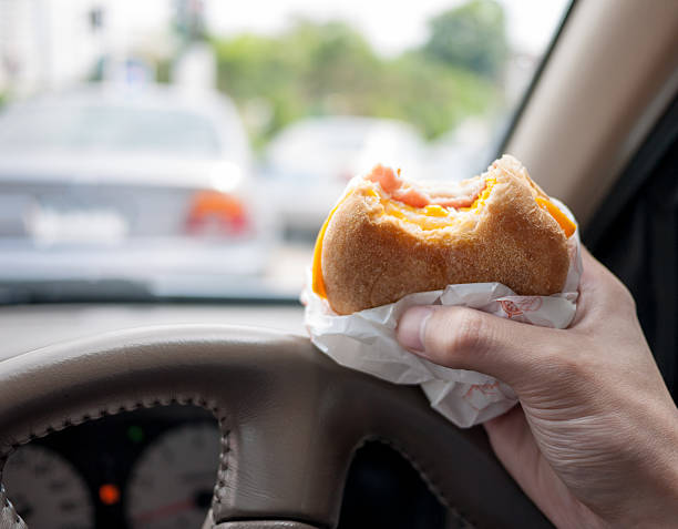 conducteur manger un hamburger dans la voiture - 9780 photos et images de collection