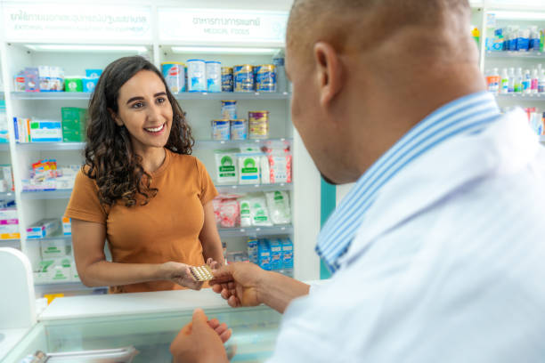 farmacéutico latino profesional de adultos medios que muestra y revisa la dosis de medicamentos con pacientes afroamericanas adultas medianas en farmacias. seguro de vida - pharmacy pharmacist customer latin american and hispanic ethnicity fotografías e imágenes de stock