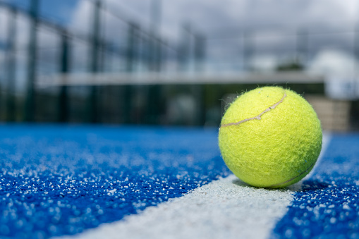 selective focus, a ball over the line of a blue paddle tennis court