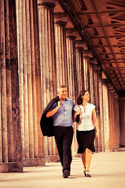 istock Elegant Couple Walking in Columns Passage - Sepia 166159224