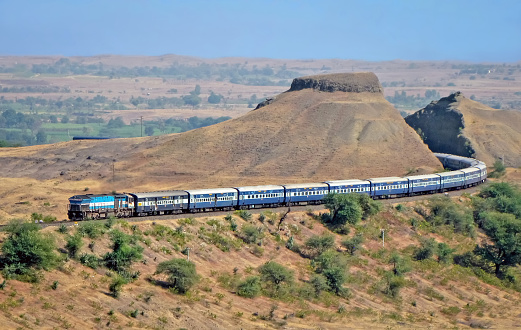 Express passenger train passing through a huge hill cutting in Adarki, Maharashtra, India.