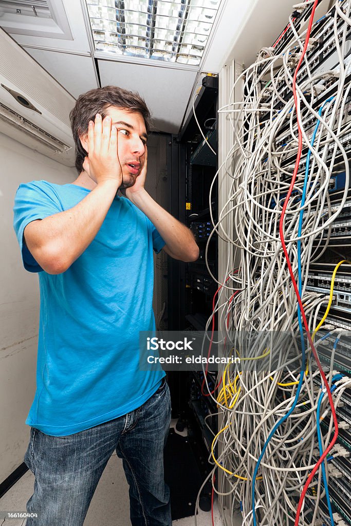 Network Cables Horror Adult man in his early 30's looking with horror on the tangled cable chaos on the server in front of him. Poor network administrator... Messy Stock Photo