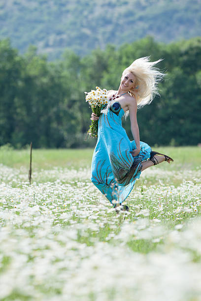 Attractive blonde in chamomile field Attractive blonde in chamomile field. Young woman with bouquet of flowers jumping in chamomile field gladiator shoe stock pictures, royalty-free photos & images