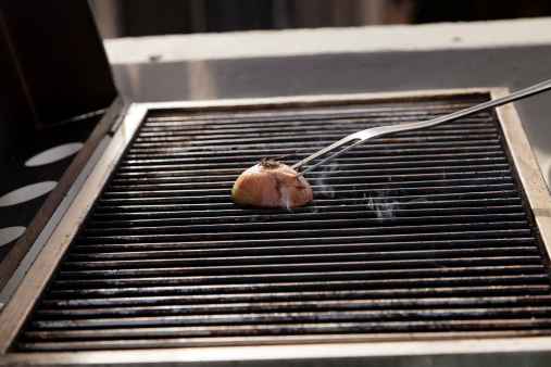 Getting the grill ready for some cooking - rubbing halved onion on the hot grate.