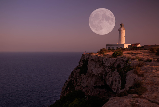 The lighthouse of La Mola with full moon in the island of Formentera in the blue hour.