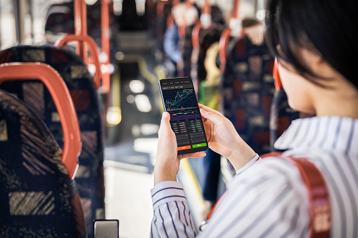The convenience of investing in crypto in that you can do it anytime anywhere.Woman using smartphone to buy cryptocurrency in the public transport, blockchain investment, decentralize and Stock market concept.