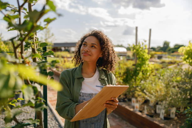 istock Smiling woman gardener making notes in clipboard while standing in garden center 1661688738