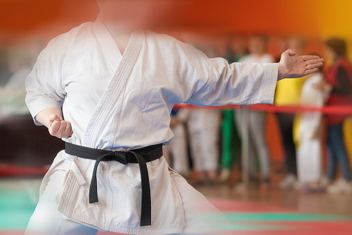 A martial artist in a white kimano with a black master belt demonstrates a technique. Added motion blur effect.