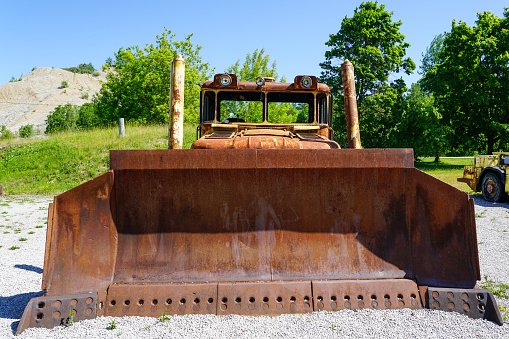 Front view of big rusty bucket of old huge heavy crawler bulldozer, abandoned vintage earthmover dozer, industrial heavy machinery