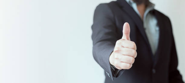 istock A businessman dressed in a suit without a tie with his thumbs up on a white-grey background. Sign of approval and satisfaction. Web banner, Copy space. 1661747544