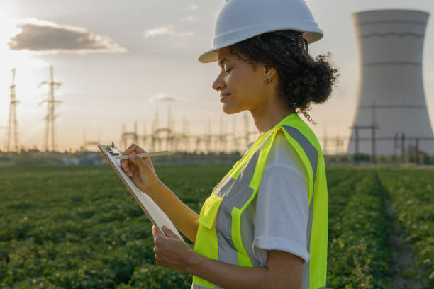 istock Female engineer constructor stands with clipboard on field on industrial enterprise background 1661785805